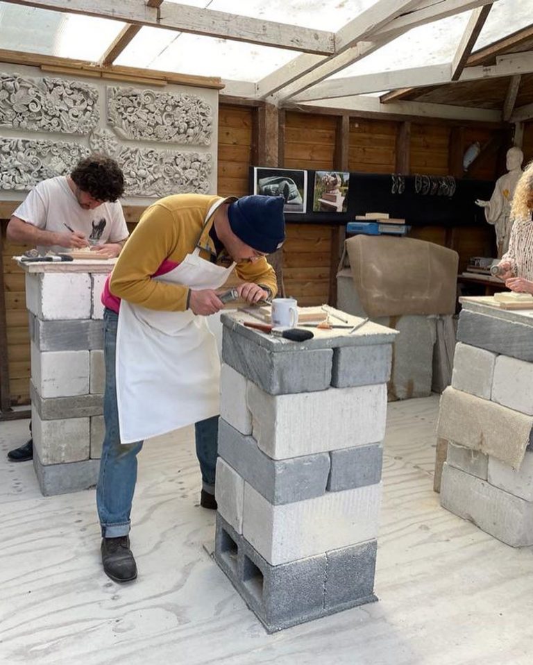 Picture of two men bent over stone blocks stone carving