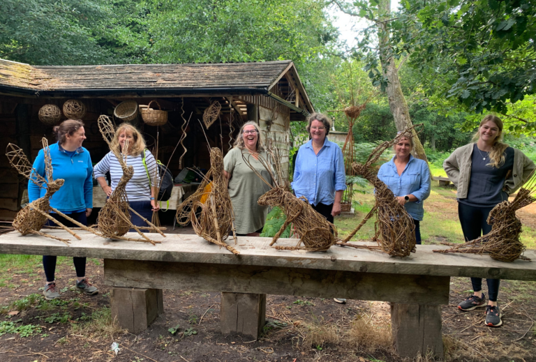 Group of ladies showing off their hand crafted willow hare sculptures at a Hedges and Hurdles workshop at Birtley Estate