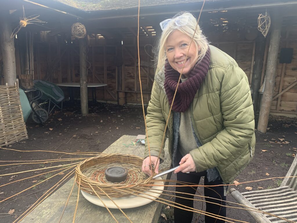 Lady weaving a willow basket with Hedges and Hurdles at the Birtley Woodland Art Space 