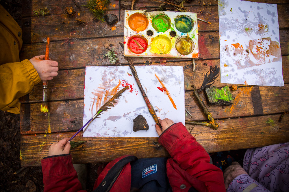 Forest School art station with colour palette (orange, light green and dark green, yellow and brown paints)
